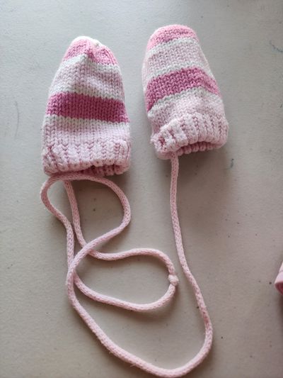 The children place pair of -knitted pink and white striped baby mittens. Infant (0-2 yrs)